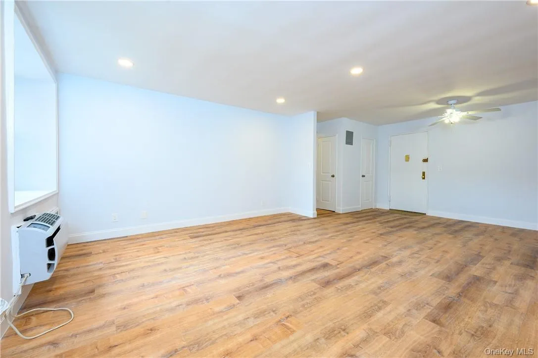 Spare room with a wall unit AC, ceiling fan, and light hardwood / wood-style floors Spare room with a wall unit AC, ceiling fan, and light hardwood / wood-style floors