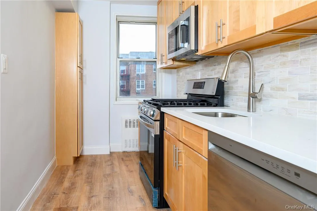 Kitchen featuring tasteful backsplash, light hardwood / wood-style flooring, stainless steel appliances, and sink Kitchen featuring tasteful backsplash, light hardwood / wood-style flooring, stainless steel appliances, and sink