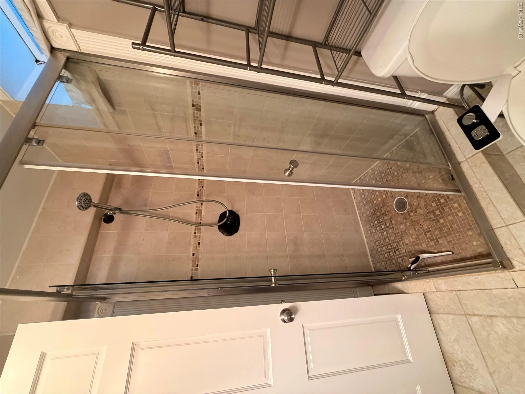 Walk-in shower with clear glass enclosure and a handheld shower fixture Walk-in shower with clear glass enclosure and a handheld shower fixture