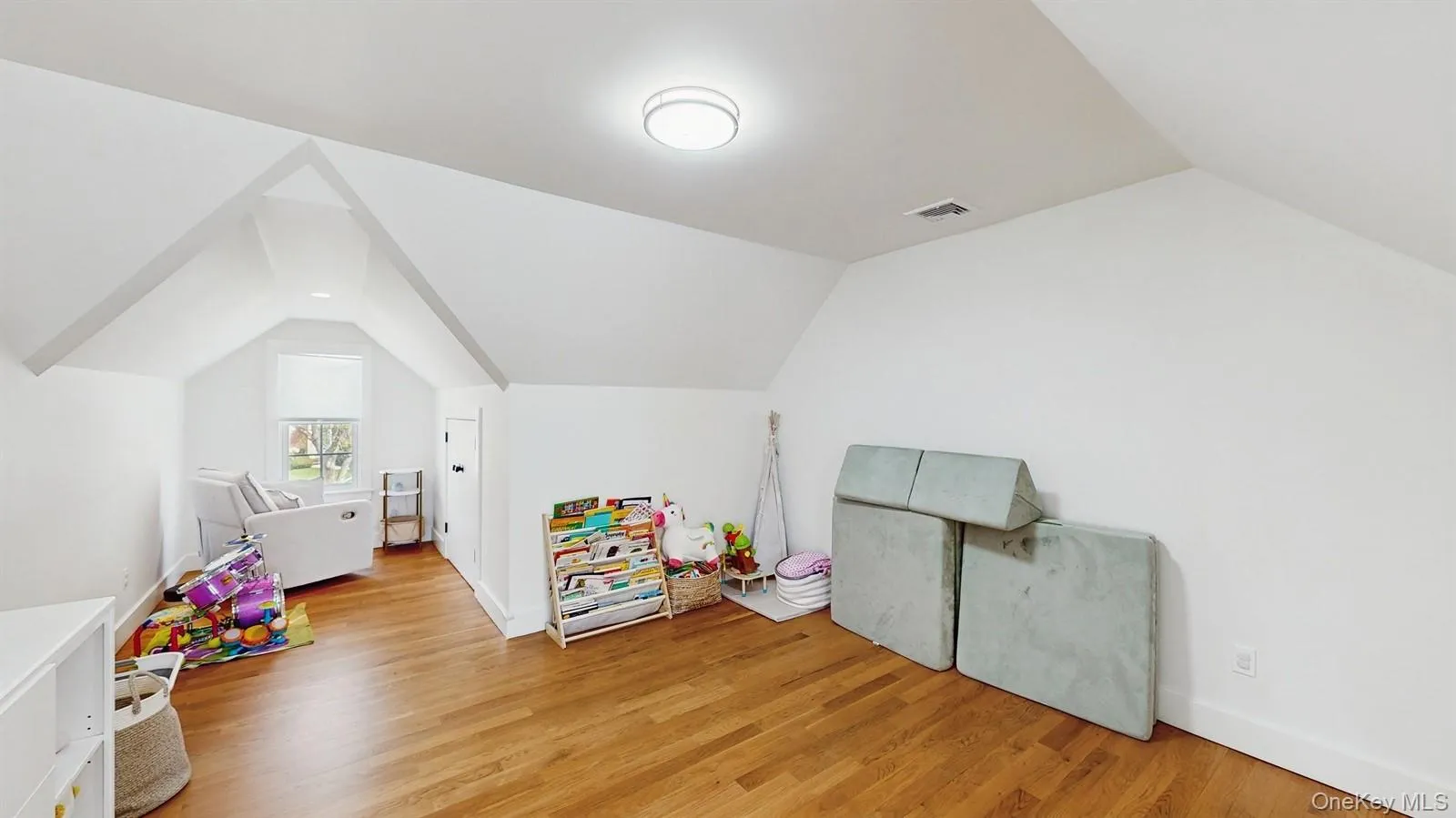 Playroom with light wood-type flooring, baseboards, vaulted ceiling, and visible vents Playroom with light wood-type flooring, baseboards, vaulted ceiling, and visible vents