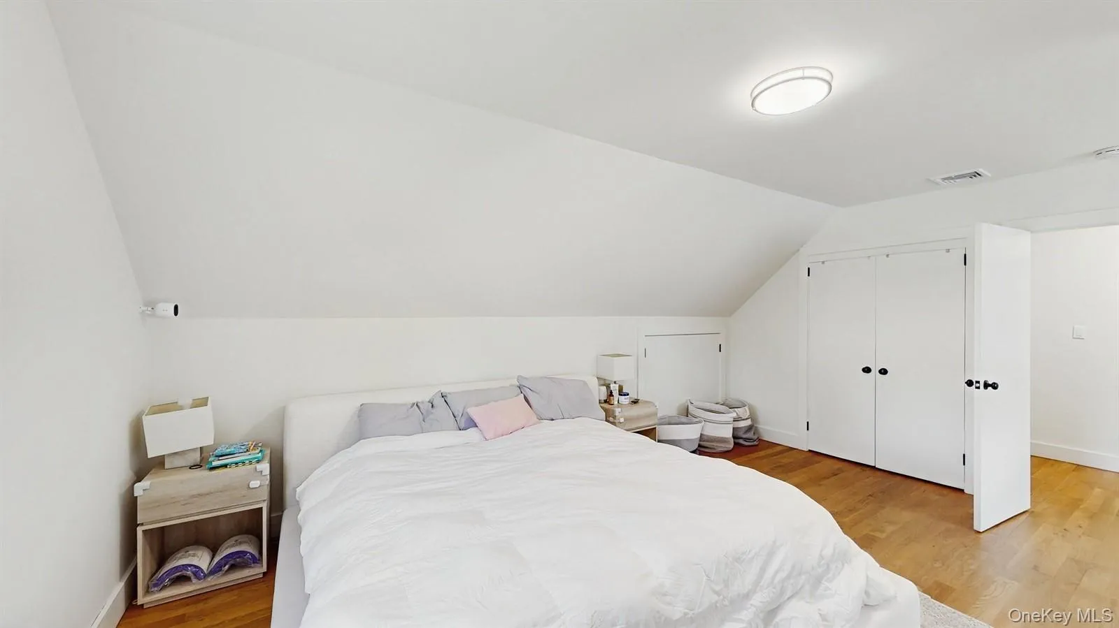 Bedroom with visible vents, baseboards, a closet, light wood-style floors, and vaulted ceiling Bedroom with visible vents, baseboards, a closet, light wood-style floors, and vaulted ceiling