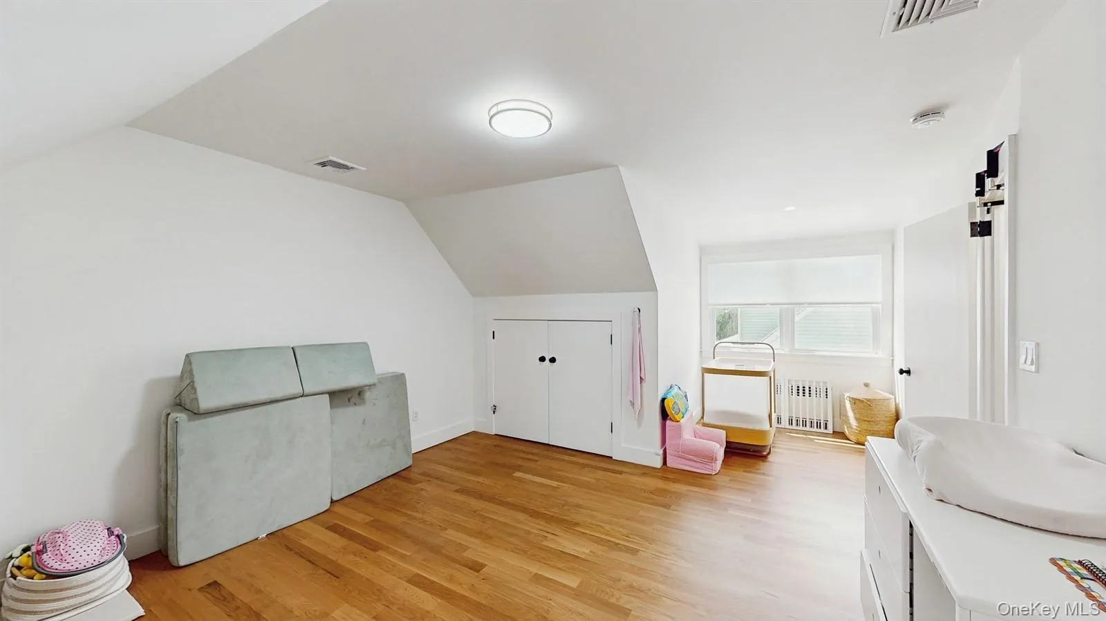 Additional living space with radiator heating unit, visible vents, vaulted ceiling, and light wood-style flooring Additional living space with radiator heating unit, visible vents, vaulted ceiling, and light wood-style flooring