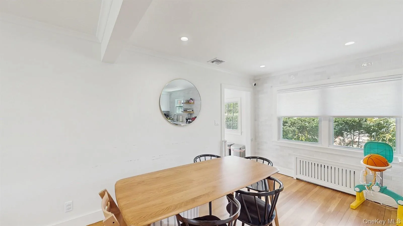 Dining room with crown molding, visible vents, radiator heating unit, and light wood finished floors Dining room with crown molding, visible vents, radiator heating unit, and light wood finished floors