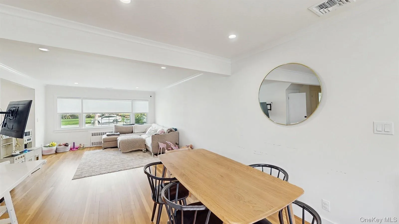 Dining space featuring visible vents, crown molding, light wood finished floors, radiator, and recessed lighting Dining space featuring visible vents, crown molding, light wood finished floors, radiator, and recessed lighting