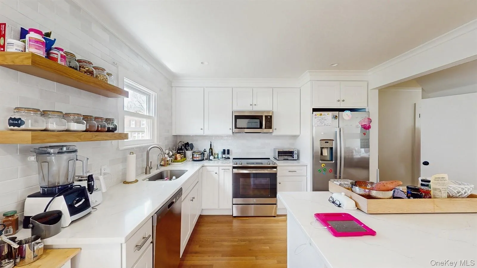 Kitchen featuring tasteful backsplash, open shelves, a sink, stainless steel appliances, and light wood-style flooring Kitchen featuring tasteful backsplash, open shelves, a sink, stainless steel appliances, and light wood-style flooring
