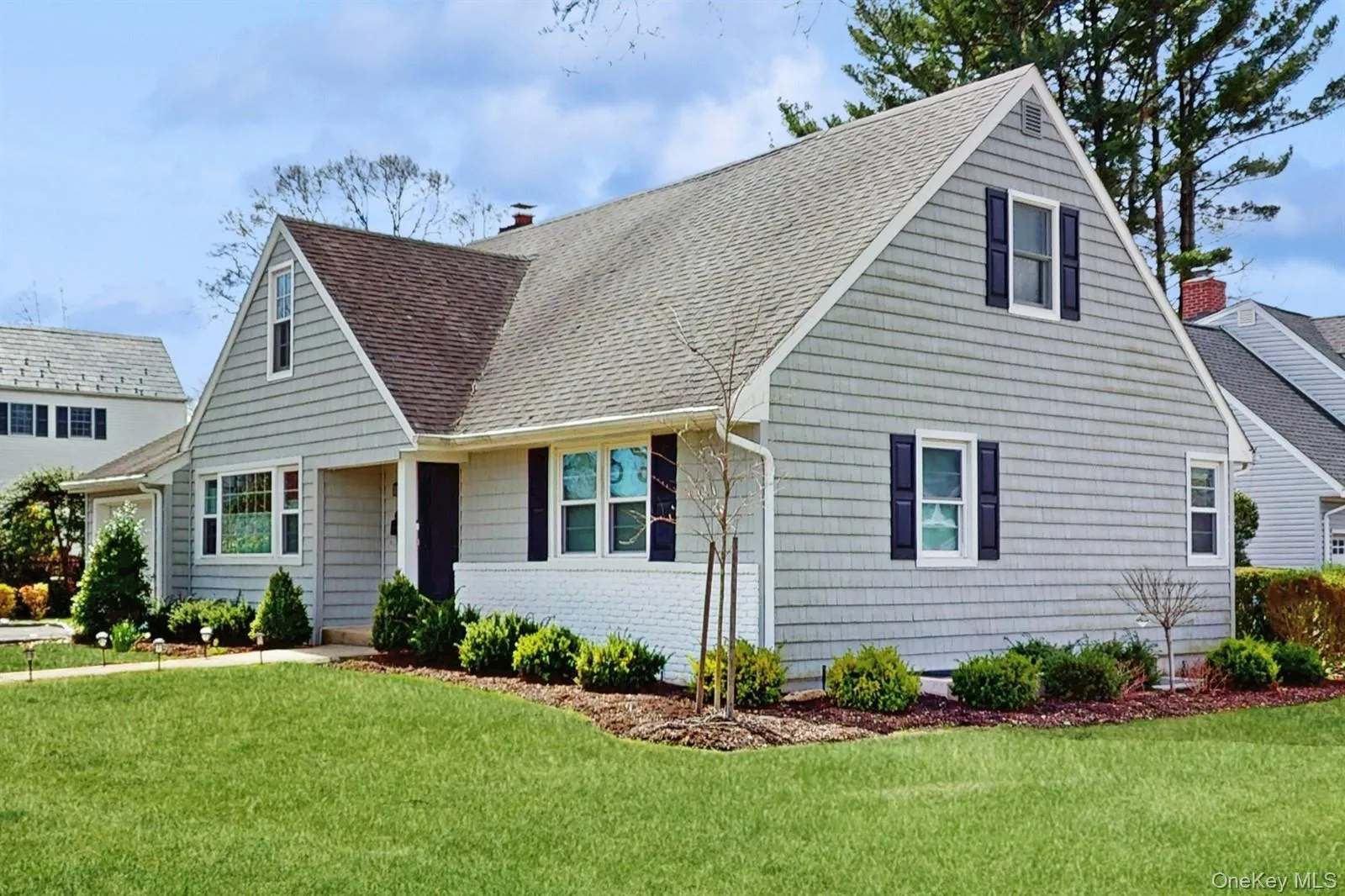 Cape cod home featuring roof with shingles, a chimney, and a front lawn Cape cod home featuring roof with shingles, a chimney, and a front lawn