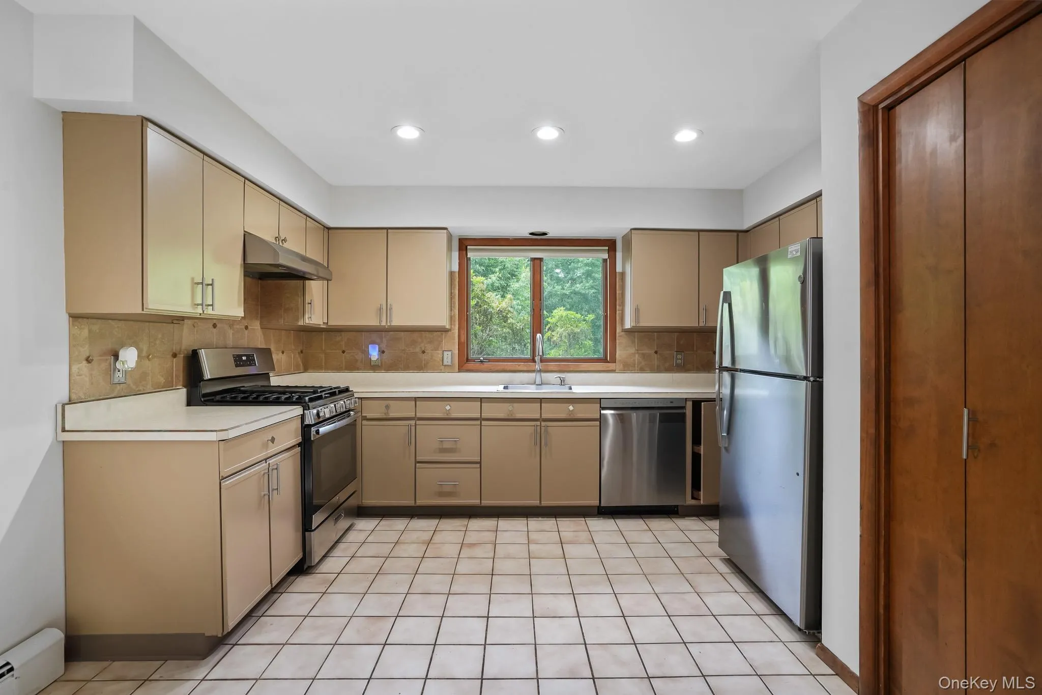 Kitchen featuring recessed lighting, light-toned cabinetry, stainless steel appliances, a tiled backsplash, and a window above the sink Kitchen featuring recessed lighting, light-toned cabinetry, stainless steel appliances, a tiled backsplash, and a window above the sink