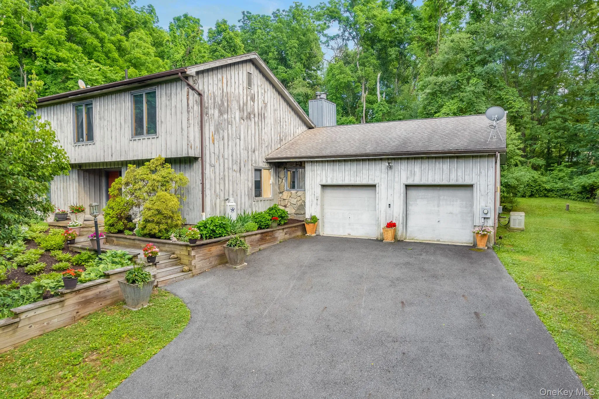 Exterior featuring vertical plank siding, a two-car garage, and a paved driveway Exterior featuring vertical plank siding, a two-car garage, and a paved driveway