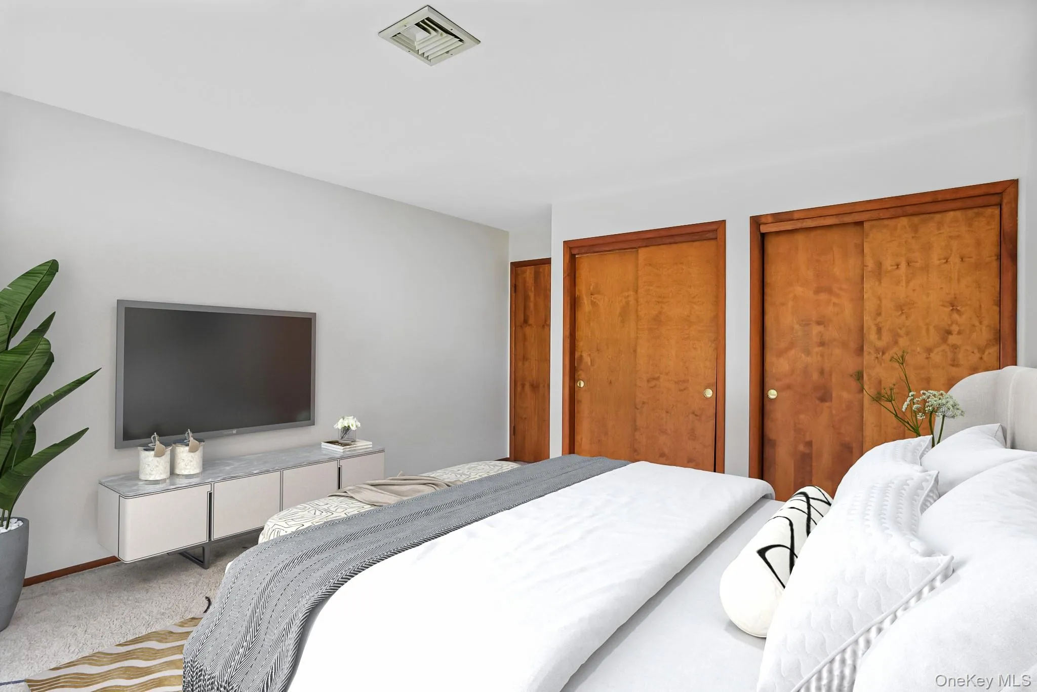 Bedroom featuring neutral wall paint, two wood-finish sliding door closets, and carpeted flooring Bedroom featuring neutral wall paint, two wood-finish sliding door closets, and carpeted flooring