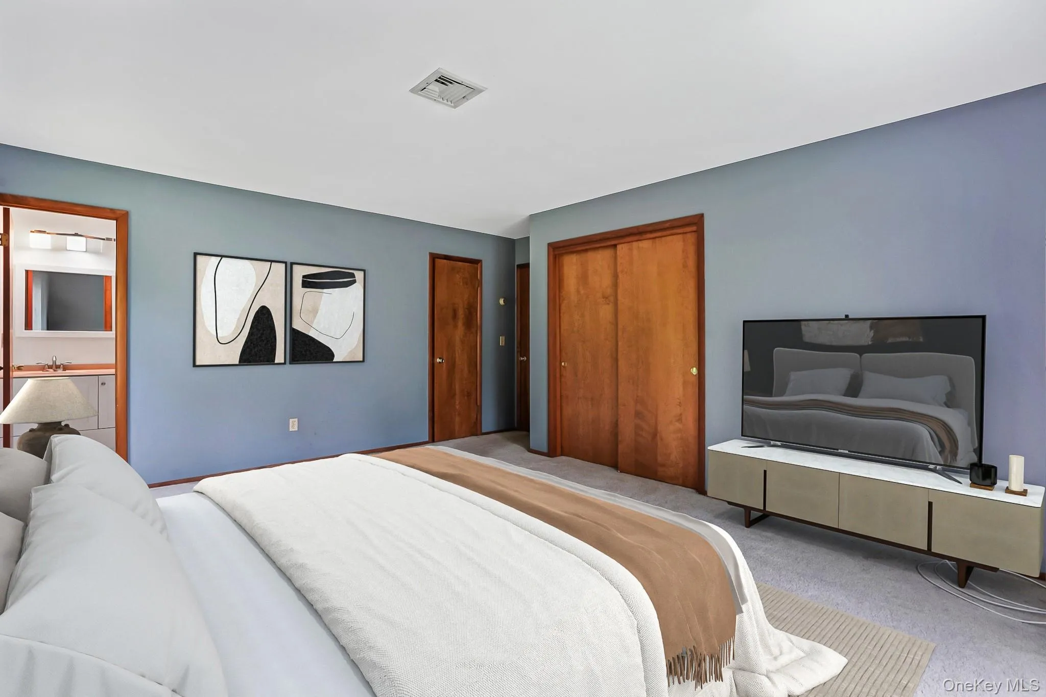 Bedroom with sliding wood-finish closet doors, light blue walls, and a recessed ceiling light Bedroom with sliding wood-finish closet doors, light blue walls, and a recessed ceiling light