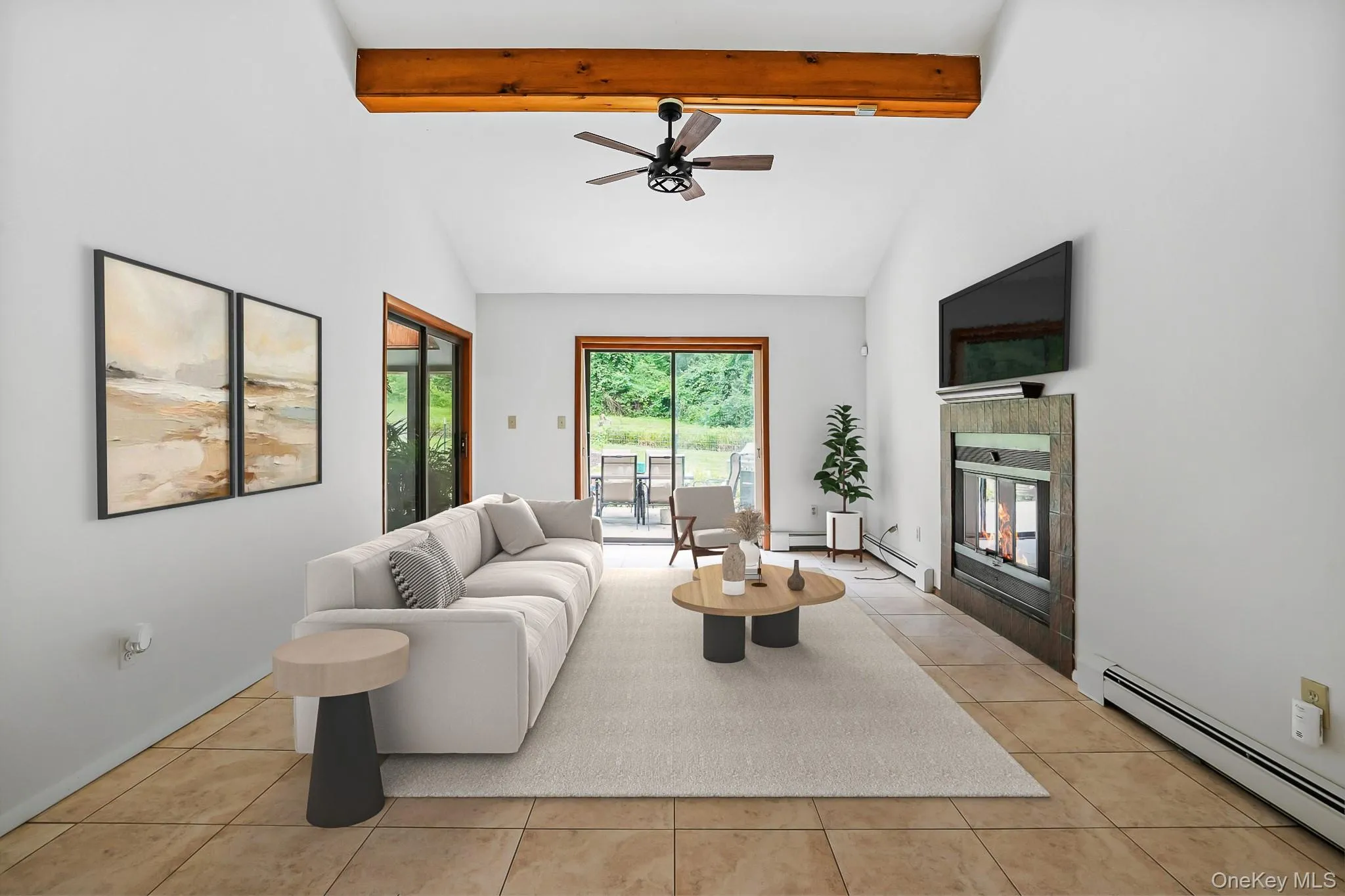 Vaulted ceilings with an exposed wood beam, a fireplace with a textured surround, light-toned tile flooring, and a sliding glass door providing exterior access Vaulted ceilings with an exposed wood beam, a fireplace with a textured surround, light-toned tile flooring, and a sliding glass door providing exterior access