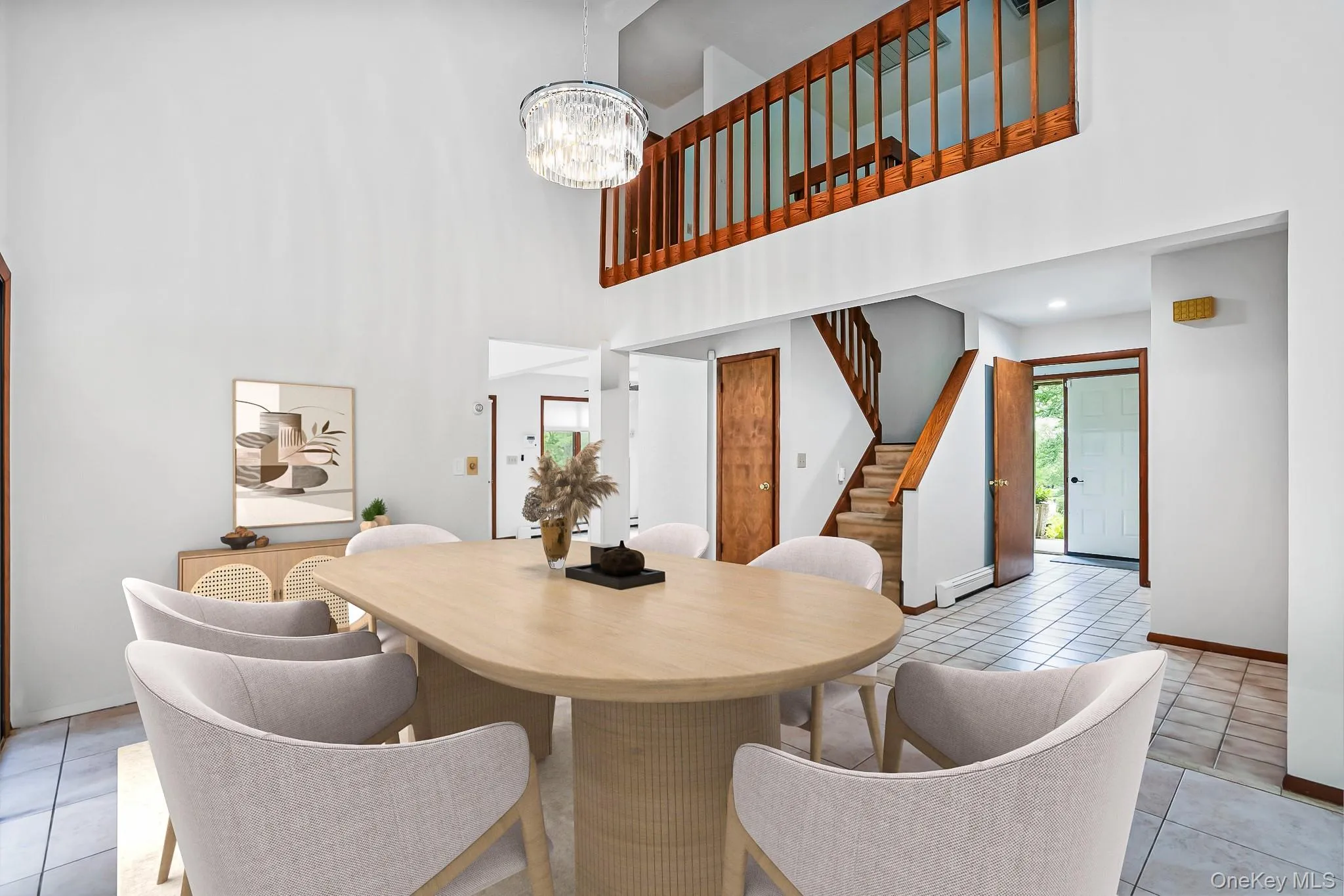 Dining area featuring a vaulted ceiling with a crystal chandelier, wood-finish flooring, and a second-story landing with wood railings Dining area featuring a vaulted ceiling with a crystal chandelier, wood-finish flooring, and a second-story landing with wood railings
