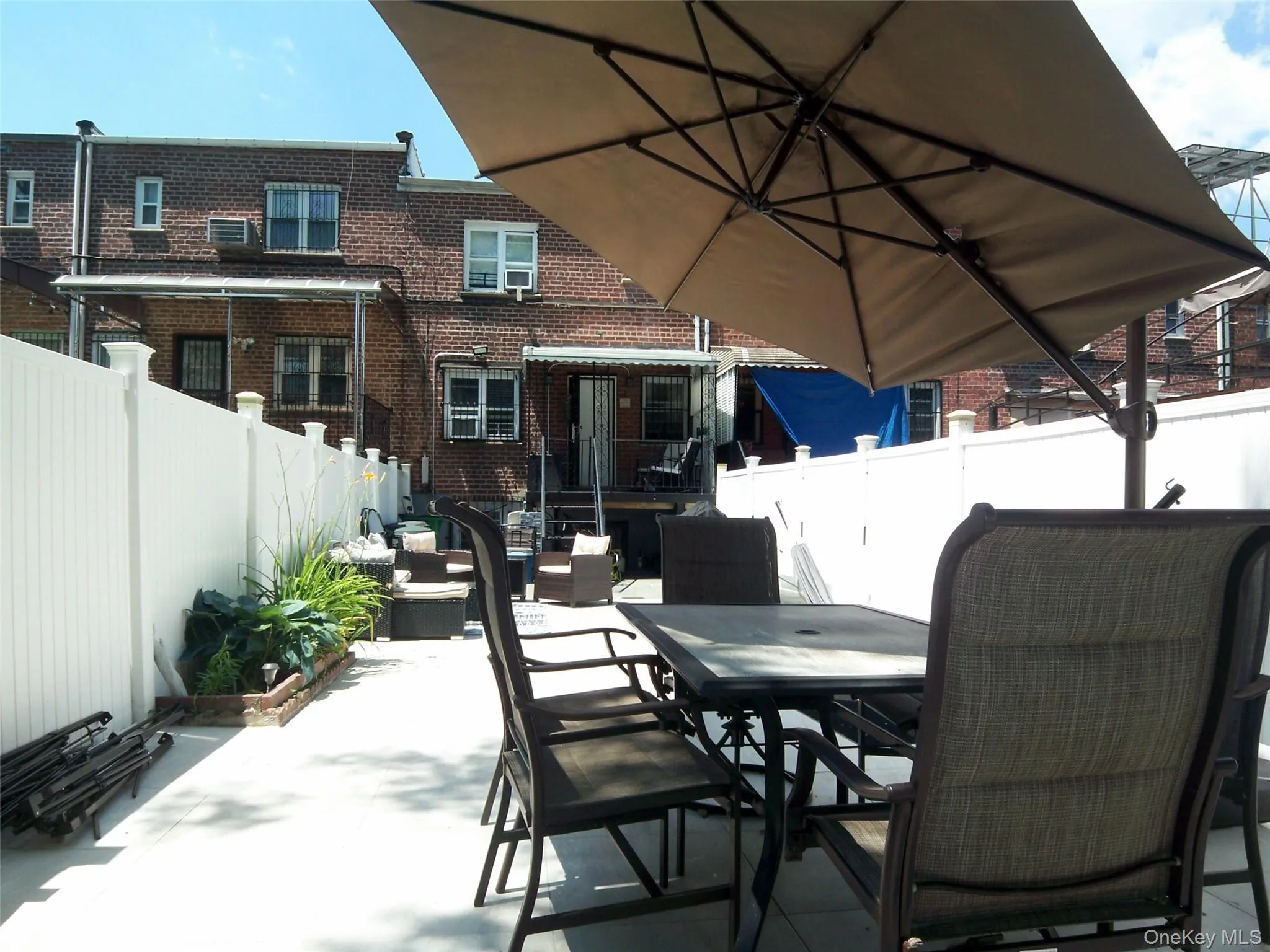 Paved outdoor patio featuring a white privacy fence and a built-in planter box Paved outdoor patio featuring a white privacy fence and a built-in planter box
