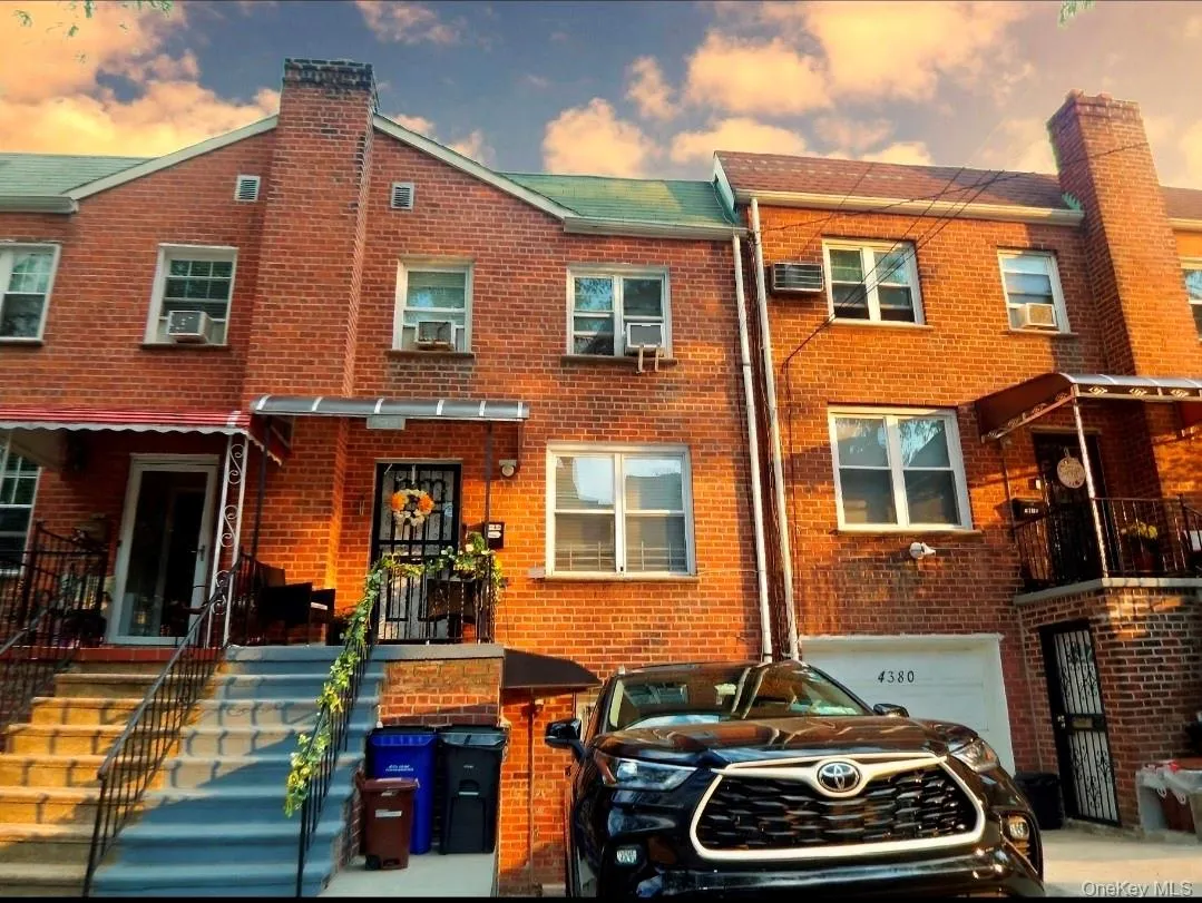 Brick facade home featuring a prominent chimney, gabled roofline, and front entry stairs with wrought iron railings Brick facade home featuring a prominent chimney, gabled roofline, and front entry stairs with wrought iron railings