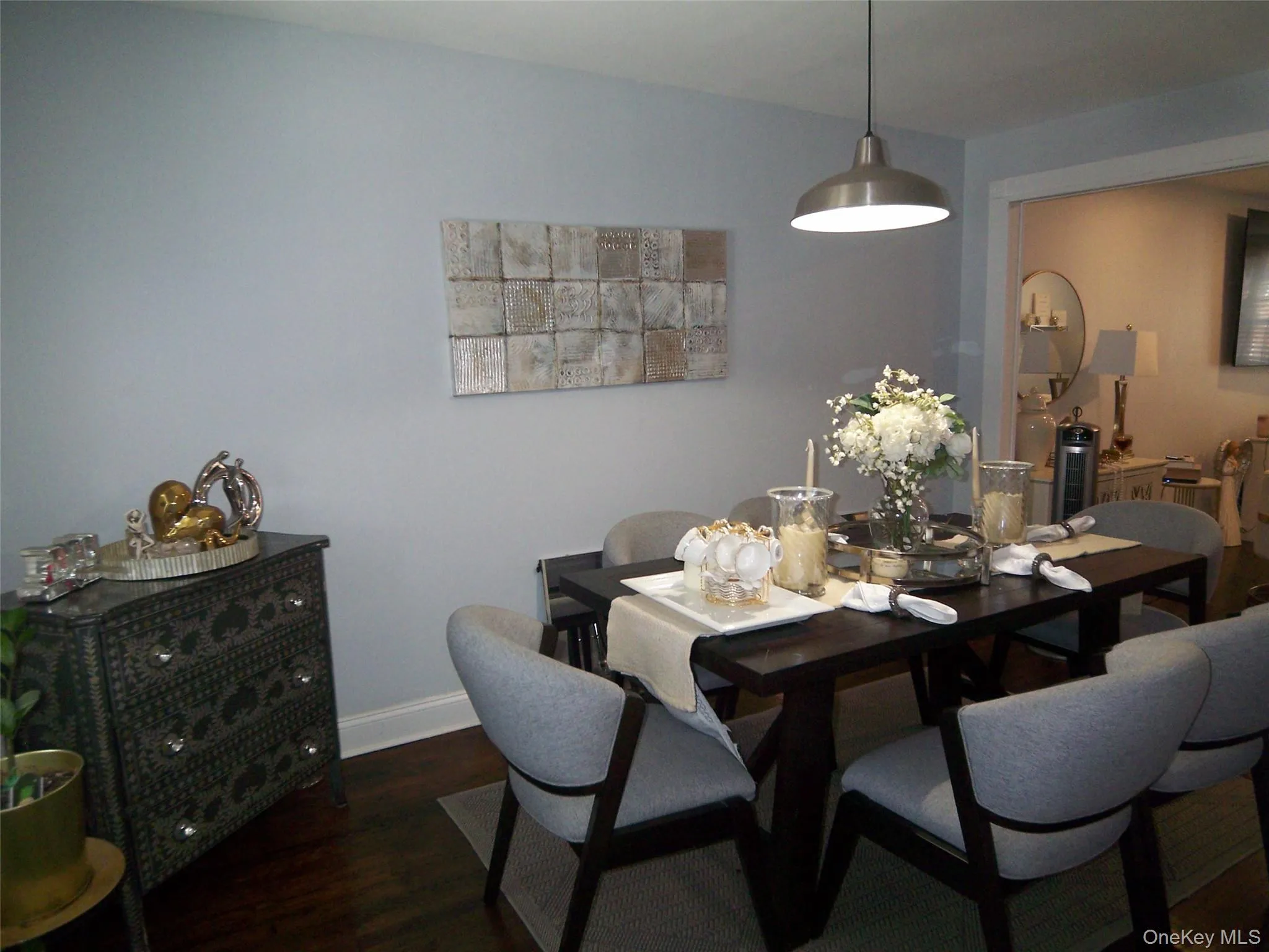Dining area featuring dark wood-finish flooring, light gray wall paint, and a modern pendant light fixture Dining area featuring dark wood-finish flooring, light gray wall paint, and a modern pendant light fixture