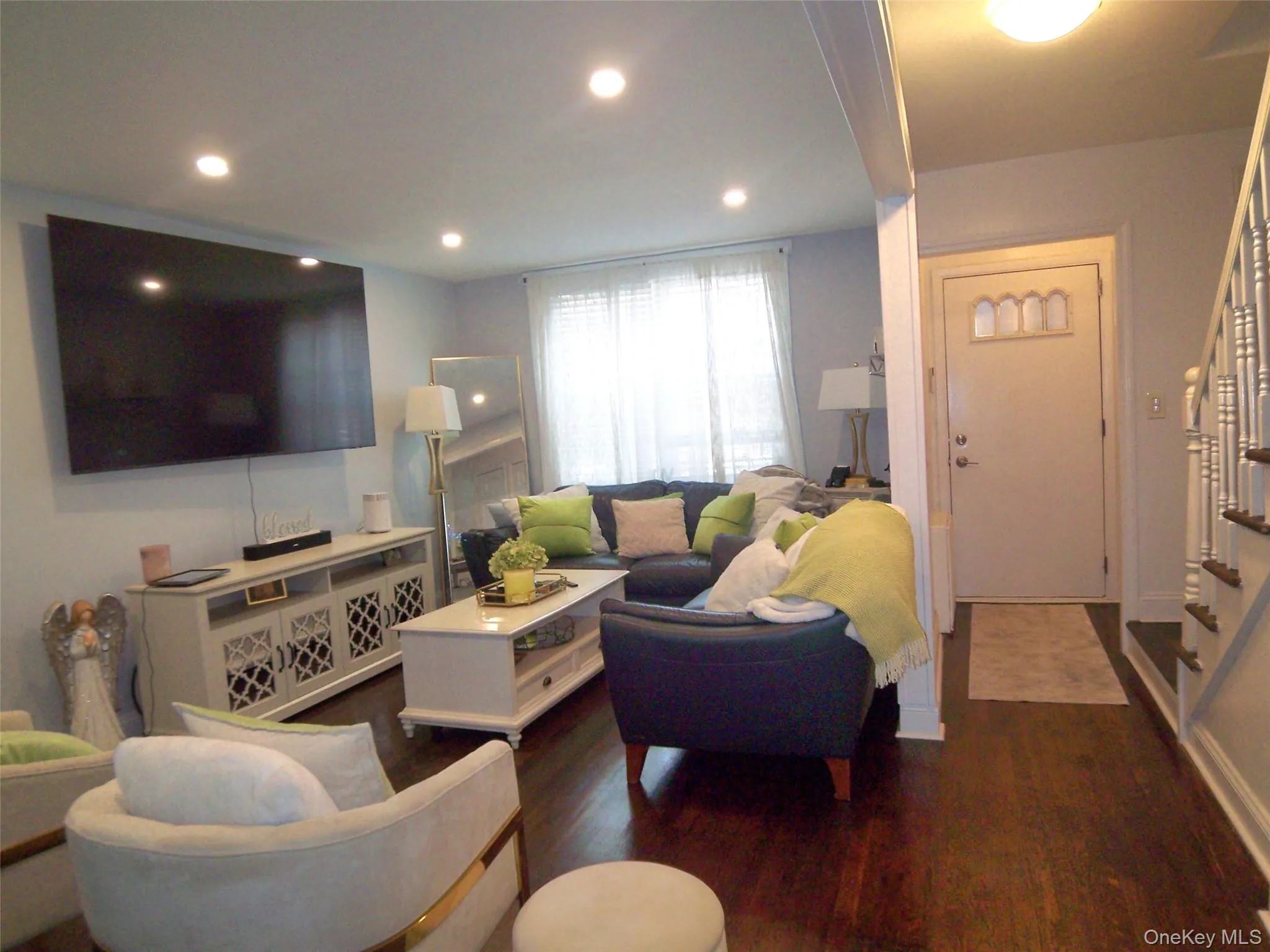 Living area featuring recessed lighting, dark wood-finish flooring, and a white front entry door with decorative glass inserts Living area featuring recessed lighting, dark wood-finish flooring, and a white front entry door with decorative glass inserts