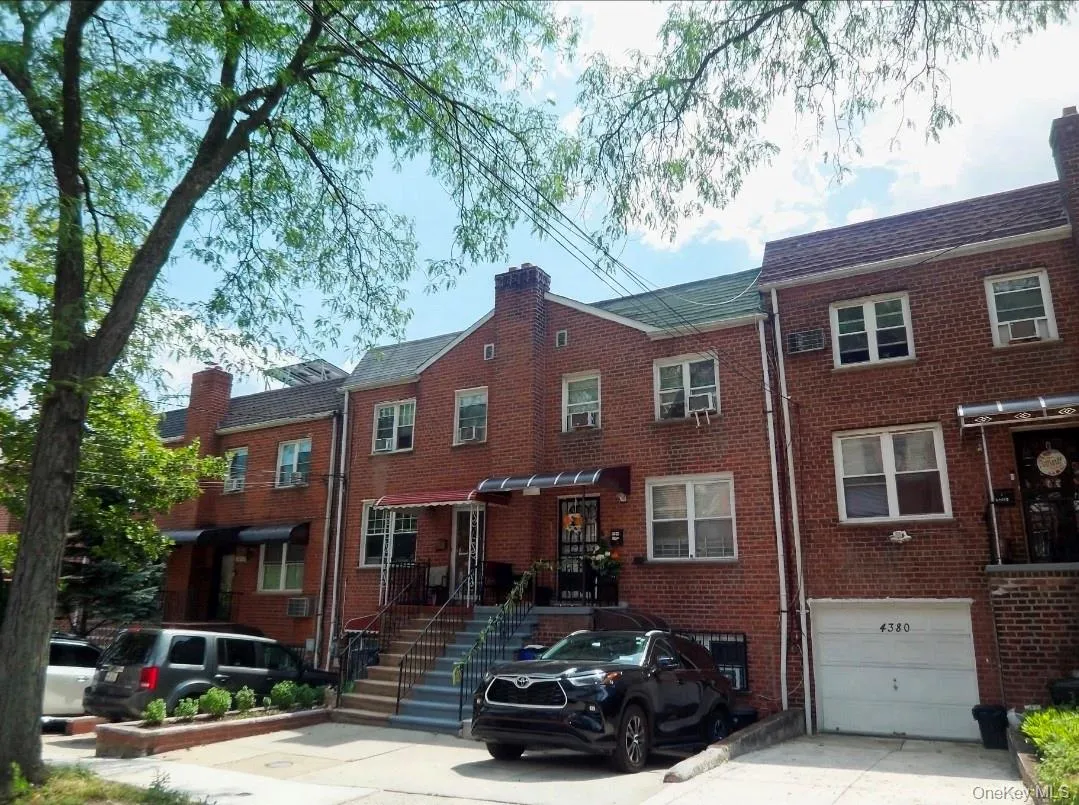Brick rowhouse featuring a pitched roof, front entry awning, and a ground-level garage Brick rowhouse featuring a pitched roof, front entry awning, and a ground-level garage