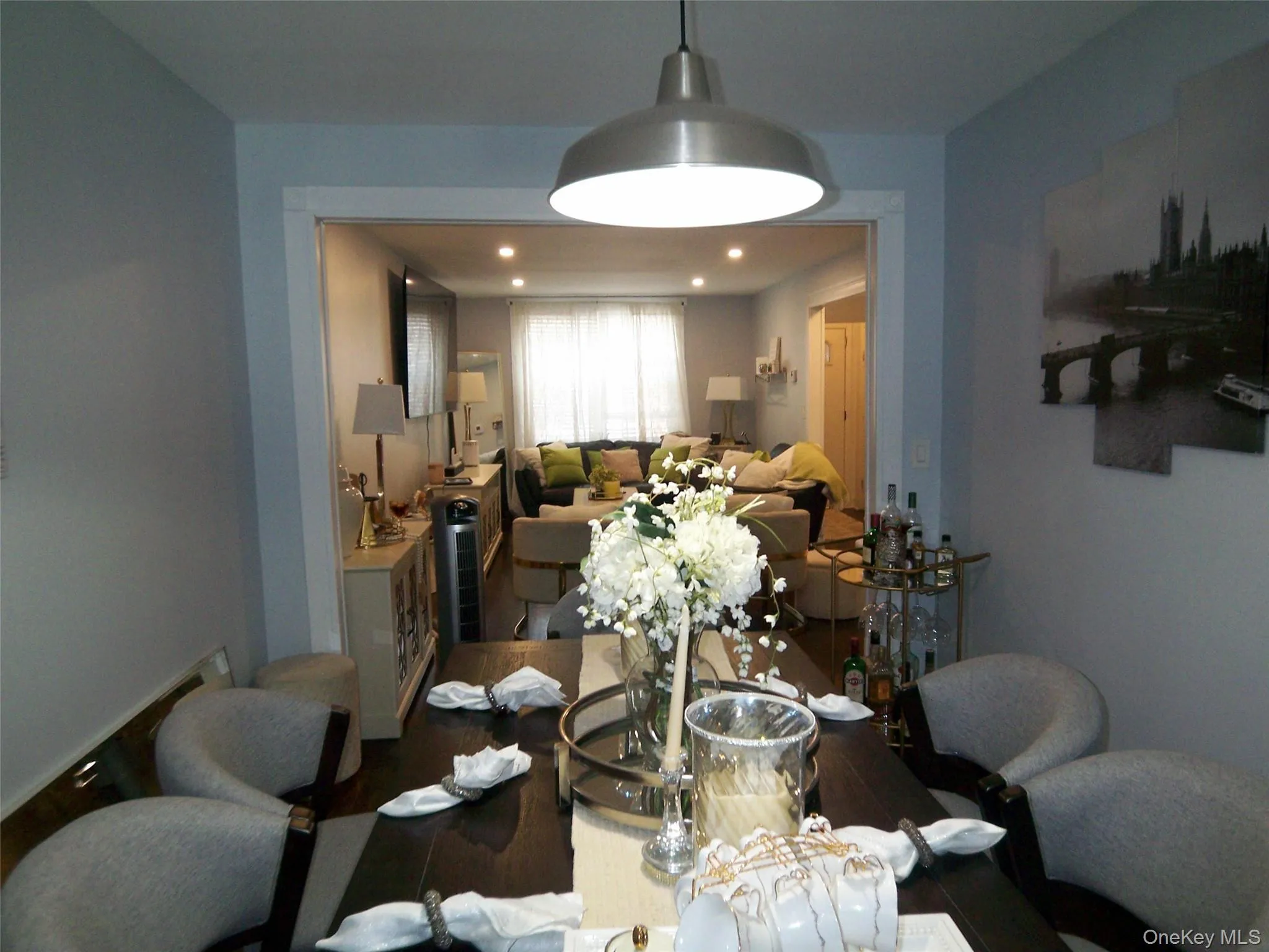 Dining area featuring a dark wood-finish table, upholstered seating, and a brushed metal pendant light fixture Dining area featuring a dark wood-finish table, upholstered seating, and a brushed metal pendant light fixture