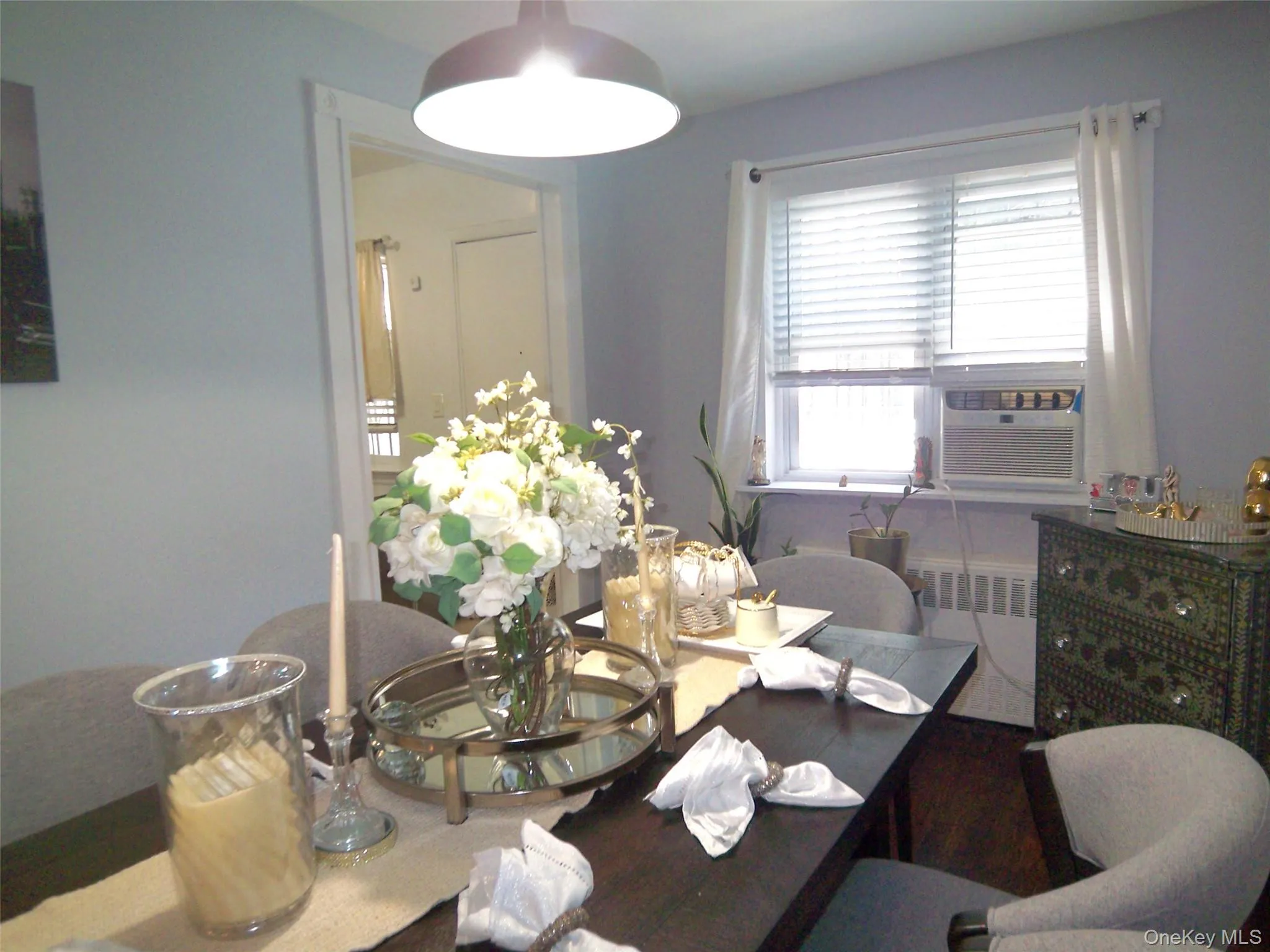 Dining area featuring a dark-finish rectangular table, overhead flush-mount lighting, light-toned wall paint, and a window with blinds Dining area featuring a dark-finish rectangular table, overhead flush-mount lighting, light-toned wall paint, and a window with blinds