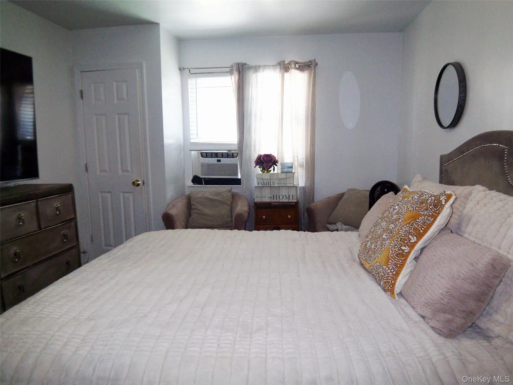Bedroom featuring a multi-panel door, window with blinds and drapes, and a built-in air conditioning unit Bedroom featuring a multi-panel door, window with blinds and drapes, and a built-in air conditioning unit