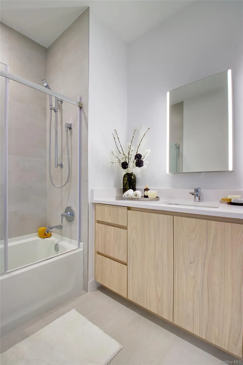 Full bathroom with enclosed tub / shower combo, vanity, and light tile patterned floors Full bathroom with enclosed tub / shower combo, vanity, and light tile patterned floors