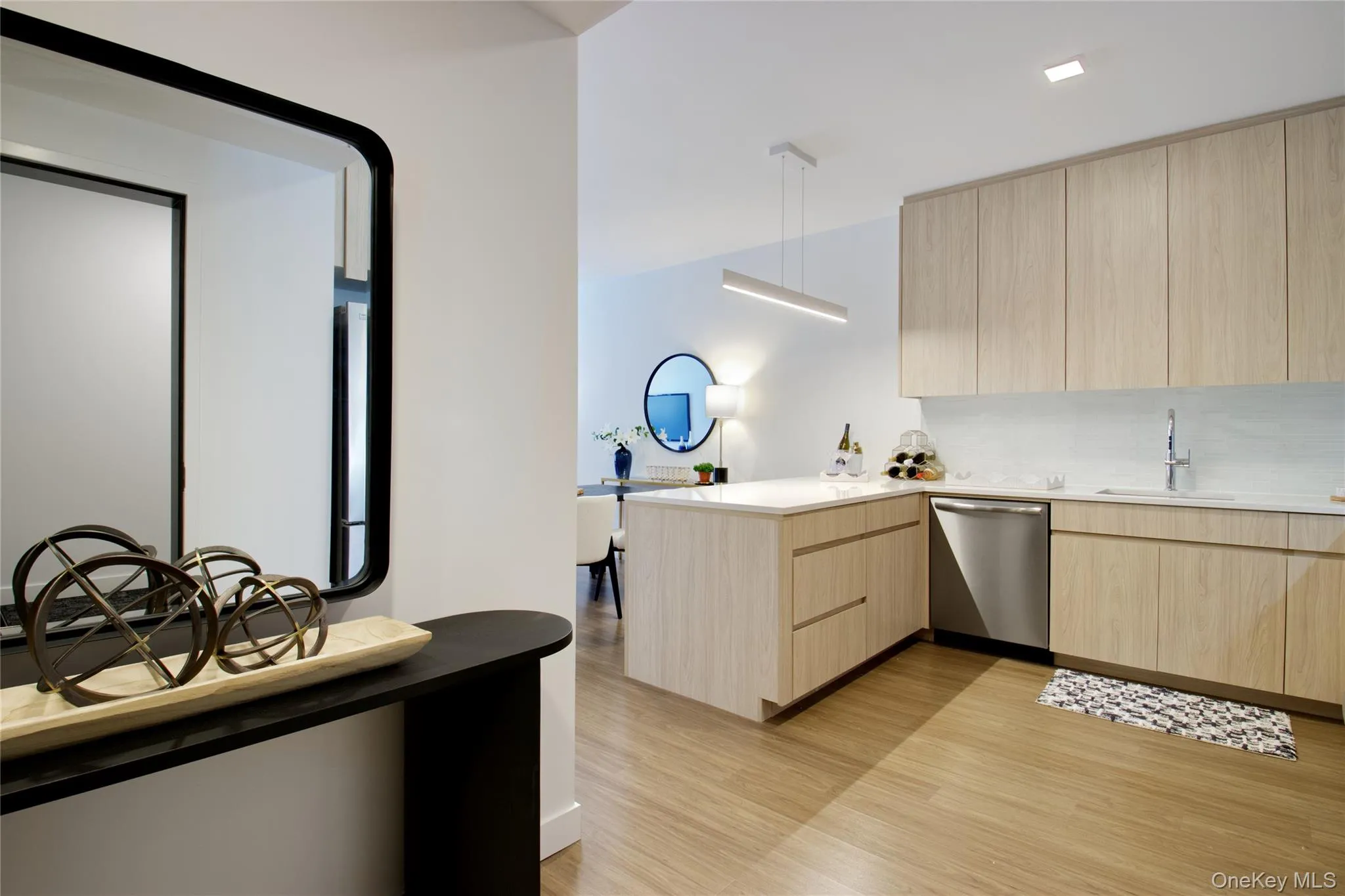 Kitchen featuring light brown cabinets, modern cabinets, a peninsula, light wood finished floors, and dishwasher Kitchen featuring light brown cabinets, modern cabinets, a peninsula, light wood finished floors, and dishwasher