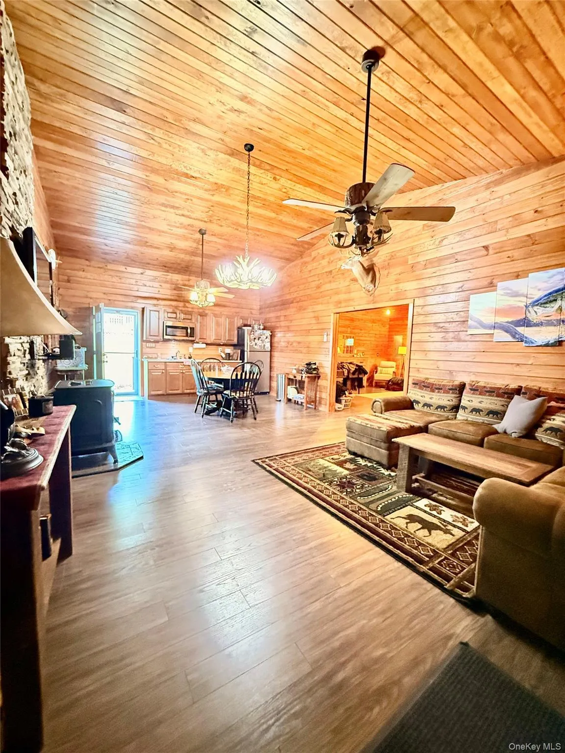 Open-concept living space featuring vaulted wood-plank ceilings and wood-finish flooring Open-concept living space featuring vaulted wood-plank ceilings and wood-finish flooring