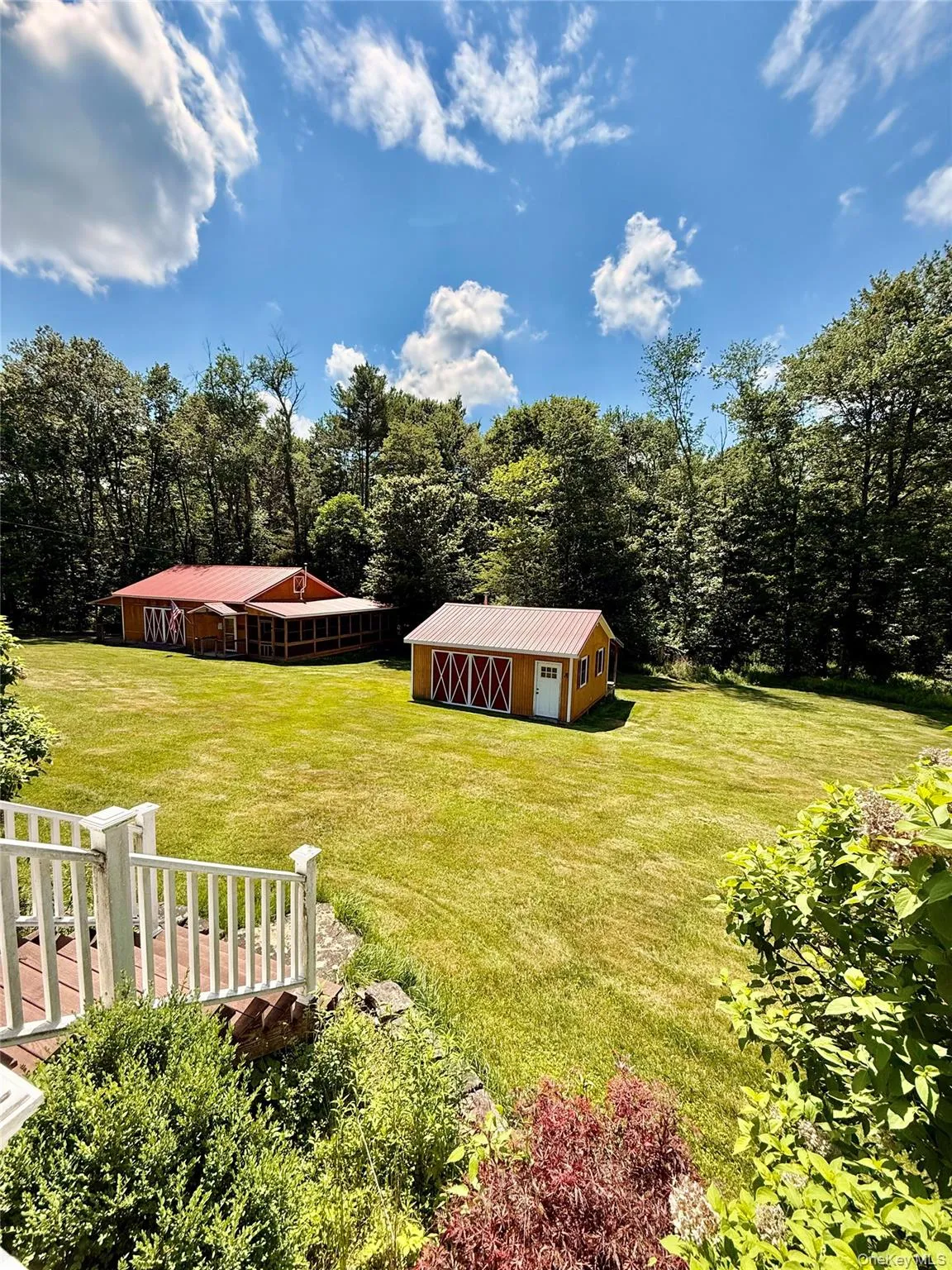 Expansive green lawn featuring two structures with red metal roofs Expansive green lawn featuring two structures with red metal roofs