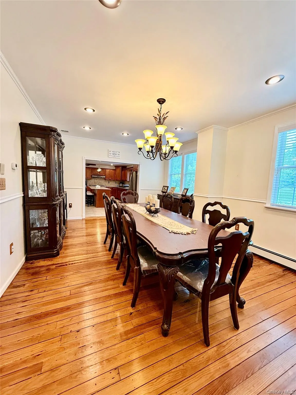 Spacious dining area featuring wood-finish flooring, a decorative chandelier, recessed lighting, and wainscoting Spacious dining area featuring wood-finish flooring, a decorative chandelier, recessed lighting, and wainscoting