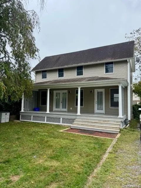 Two-story residence featuring light-colored siding and a covered front porch Two-story residence featuring light-colored siding and a covered front porch