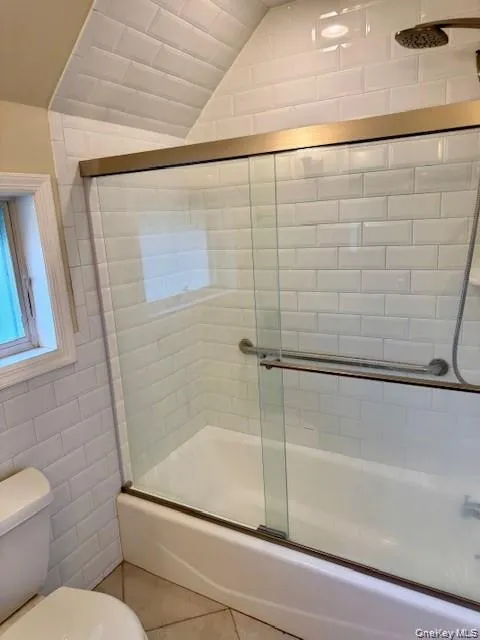 Bathtub with full subway tile surround, sliding glass shower doors, and an oil-rubbed bronze showerhead Bathtub with full subway tile surround, sliding glass shower doors, and an oil-rubbed bronze showerhead