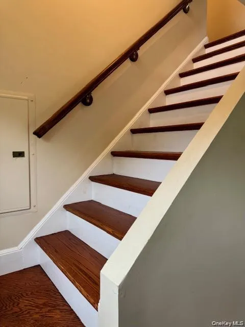 Staircase featuring wood-finish treads, white risers, and a dark wood handrail Staircase featuring wood-finish treads, white risers, and a dark wood handrail