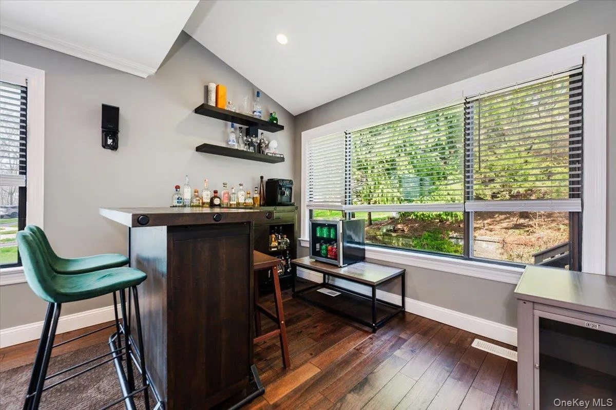 Bar featuring a dry bar, dark wood finished floors, baseboards, lofted ceiling, and ornamental molding Bar featuring a dry bar, dark wood finished floors, baseboards, lofted ceiling, and ornamental molding