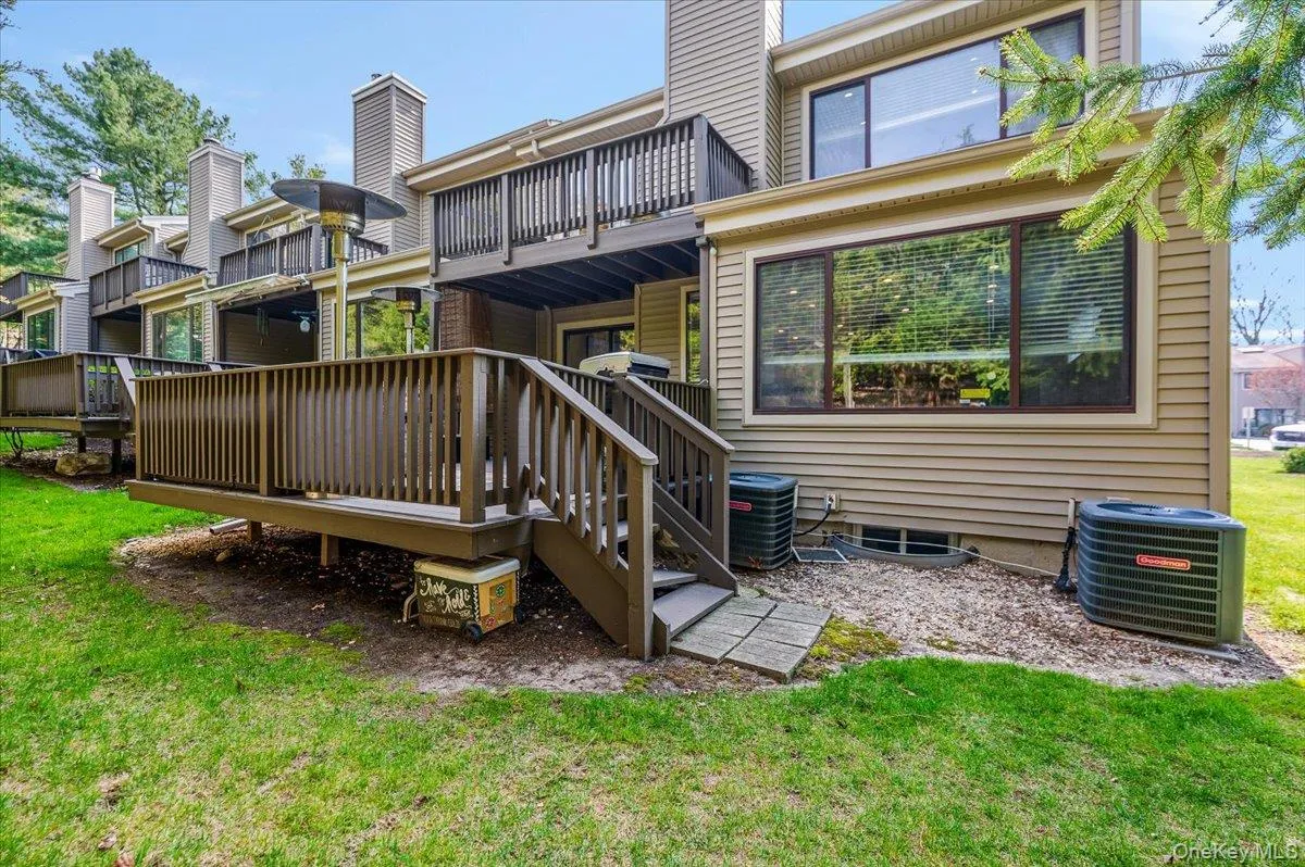 Back of property featuring a yard, a deck, cooling unit, and a balcony Back of property featuring a yard, a deck, cooling unit, and a balcony