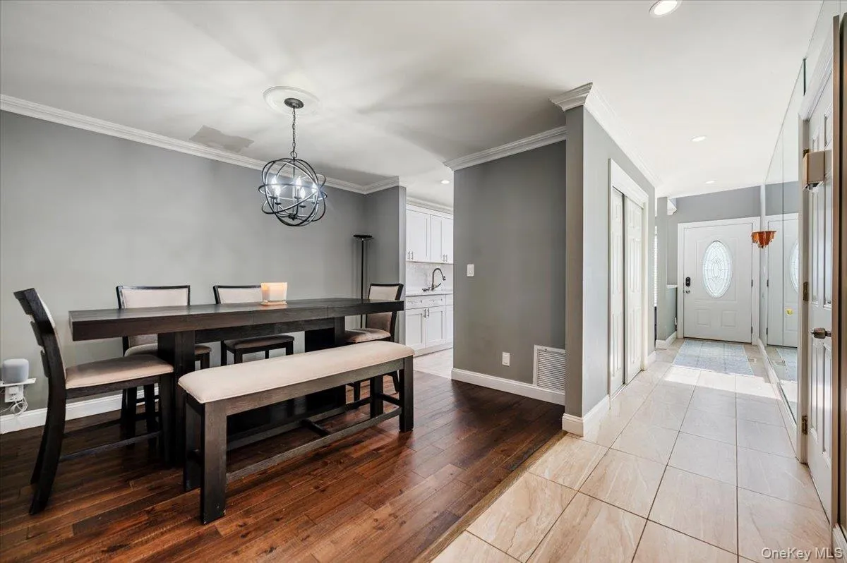 Dining room with crown molding, visible vents, baseboards, a chandelier, and light wood finished floors Dining room with crown molding, visible vents, baseboards, a chandelier, and light wood finished floors