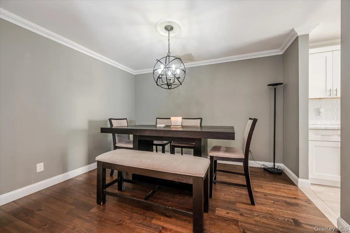 Dining area with crown molding, baseboards, an inviting chandelier, and dark wood-style floors Dining area with crown molding, baseboards, an inviting chandelier, and dark wood-style floors