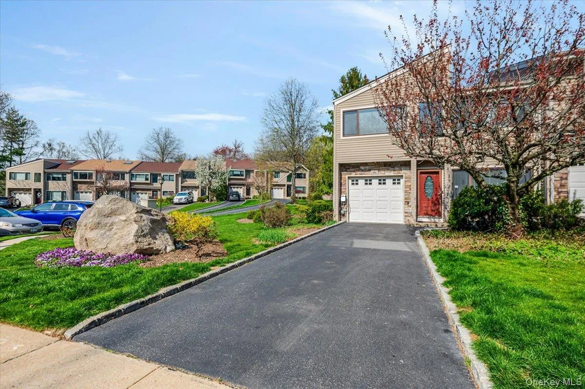 View of front facade featuring a garage, a front lawn, stone siding, driveway, and a residential view View of front facade featuring a garage, a front lawn, stone siding, driveway, and a residential view