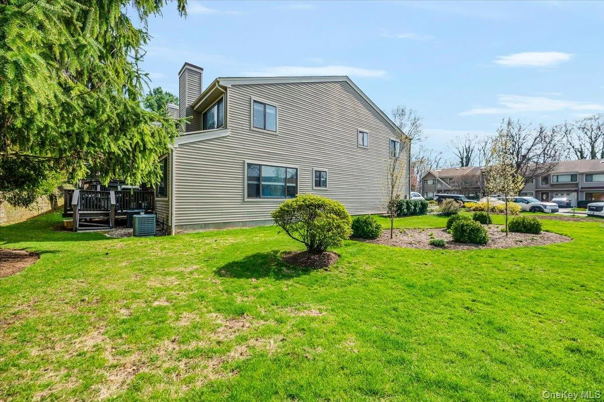 Rear view of house with a lawn, a wooden deck, a chimney, and central AC Rear view of house with a lawn, a wooden deck, a chimney, and central AC