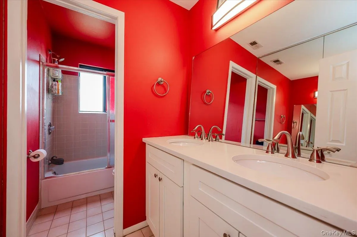 Full bath with a sink, tile patterned flooring, double vanity, baseboards, and visible vents Full bath with a sink, tile patterned flooring, double vanity, baseboards, and visible vents