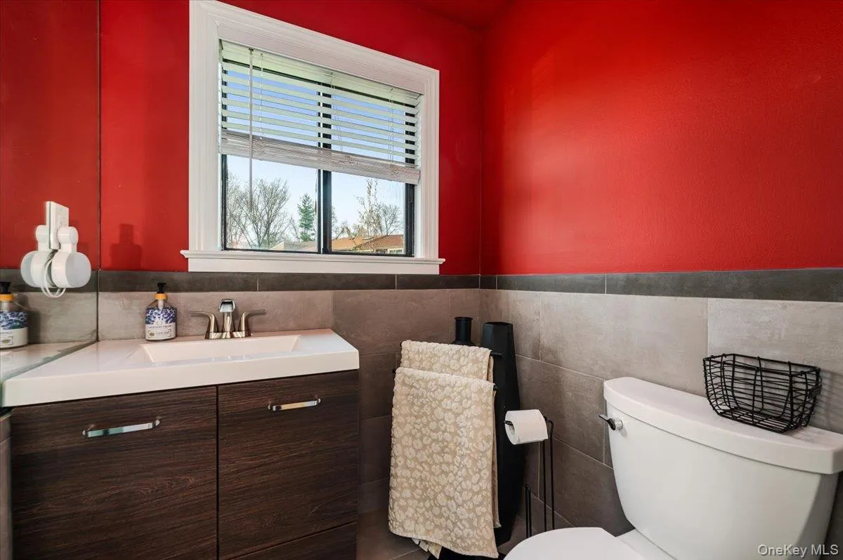Bathroom with toilet, tile walls, wainscoting, and vanity Bathroom with toilet, tile walls, wainscoting, and vanity