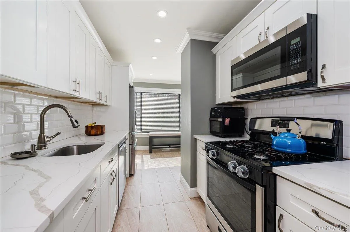 Kitchen featuring crown molding, tile backsplash, stone countertop and stainless steel appliances Kitchen featuring crown molding, tile backsplash, stone countertop and stainless steel appliances