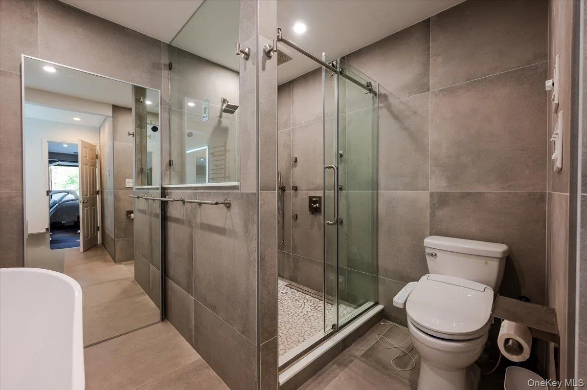 Ensuite bathroom with vanity, toilet, tile walls, recessed lighting, and a shower stall Ensuite bathroom with vanity, toilet, tile walls, recessed lighting, and a shower stall