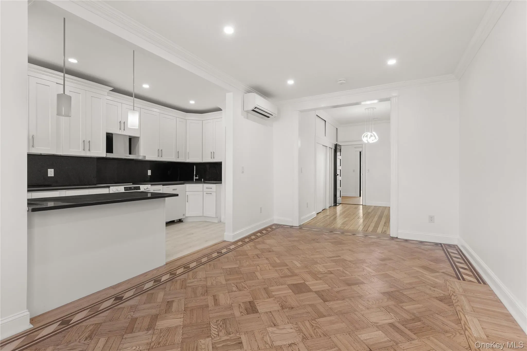Open-concept living area featuring intricate parquet wood flooring with a decorative border Open-concept living area featuring intricate parquet wood flooring with a decorative border