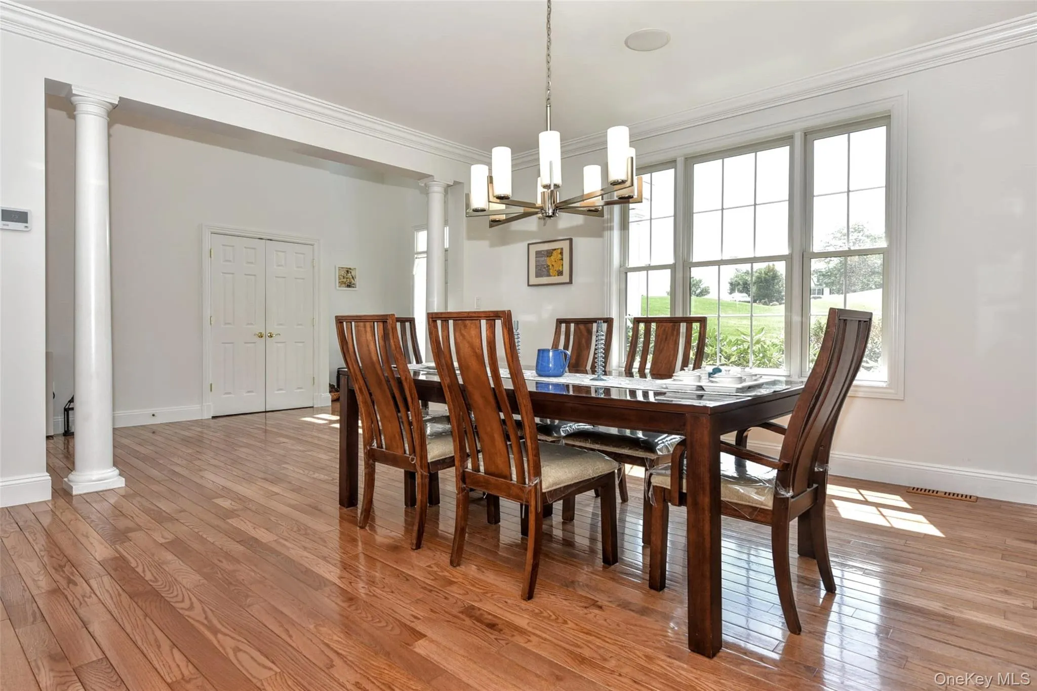 Dining area featuring wood-finish flooring, a contemporary chandelier, and large windows Dining area featuring wood-finish flooring, a contemporary chandelier, and large windows