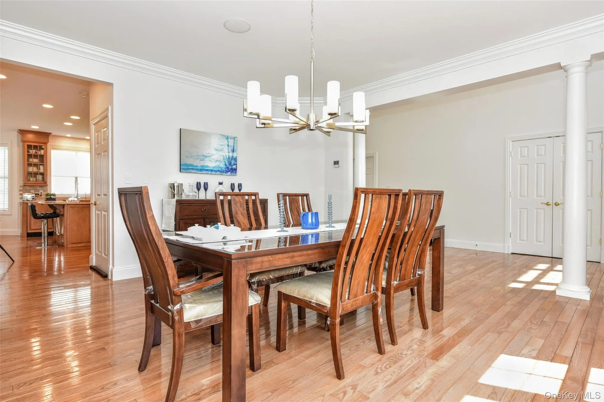 Bright dining area featuring hardwood flooring, crown molding, and a contemporary chandelier Bright dining area featuring hardwood flooring, crown molding, and a contemporary chandelier