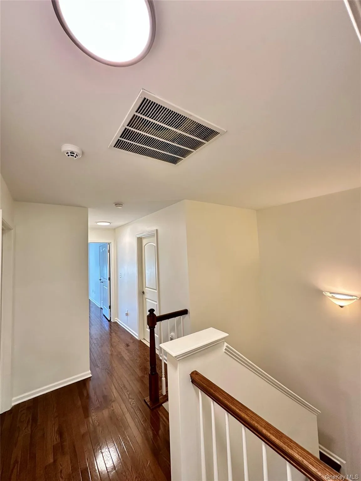 Hallway with an upstairs landing and dark wood-style flooring Hallway with an upstairs landing and dark wood-style flooring