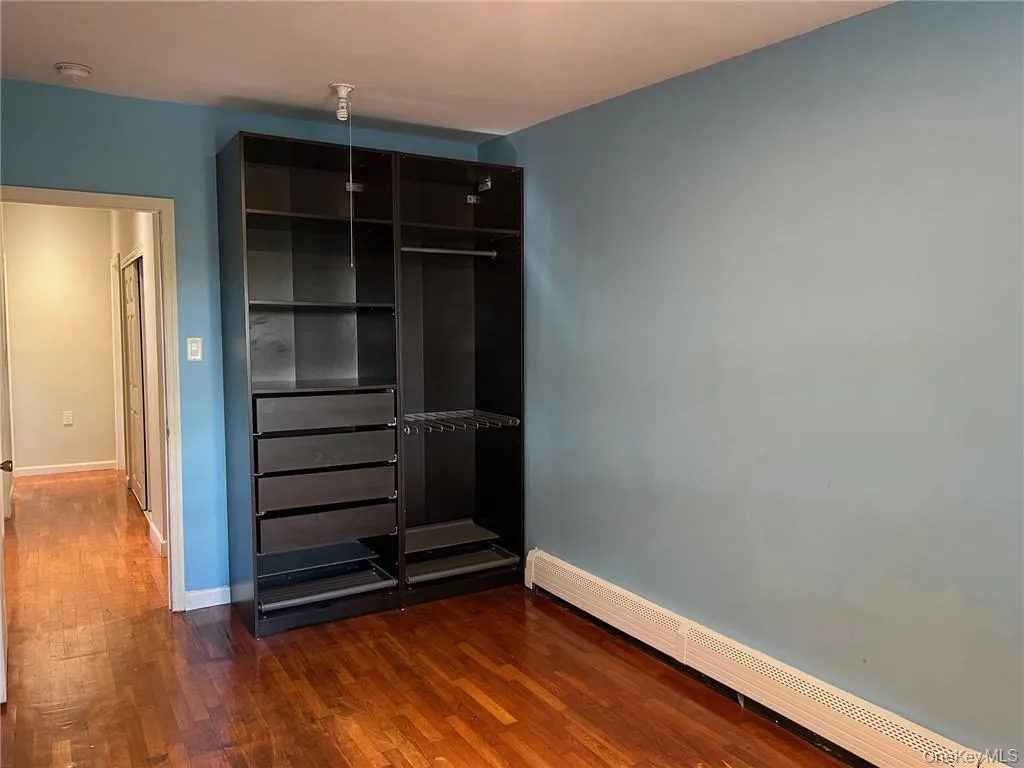 Unfurnished bedroom featuring a baseboard heating unit and dark hardwood / wood-style flooring Unfurnished bedroom featuring a baseboard heating unit and dark hardwood / wood-style flooring