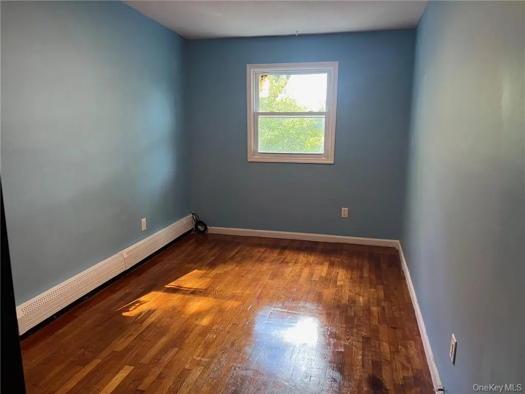Spare room featuring a baseboard radiator and hardwood / wood-style floors Spare room featuring a baseboard radiator and hardwood / wood-style floors
