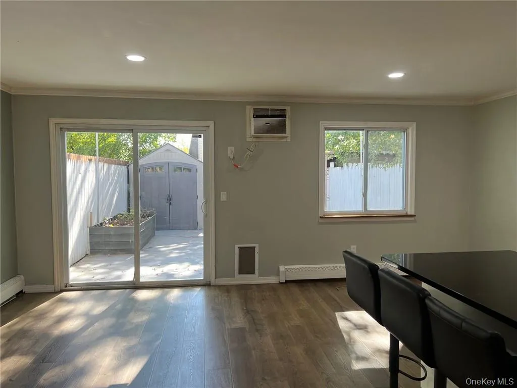 Doorway to outside featuring baseboard heating, crown molding, dark wood-type flooring, and a wealth of natural light Doorway to outside featuring baseboard heating, crown molding, dark wood-type flooring, and a wealth of natural light