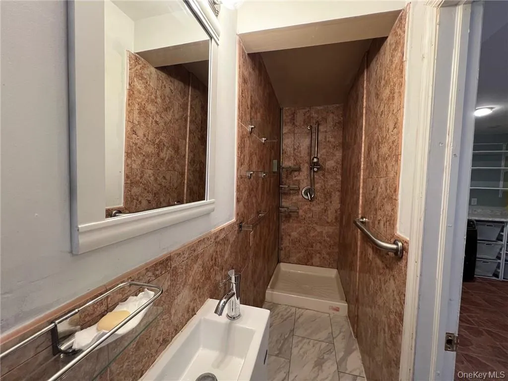 Bathroom featuring tiled shower and tile walls Bathroom featuring tiled shower and tile walls